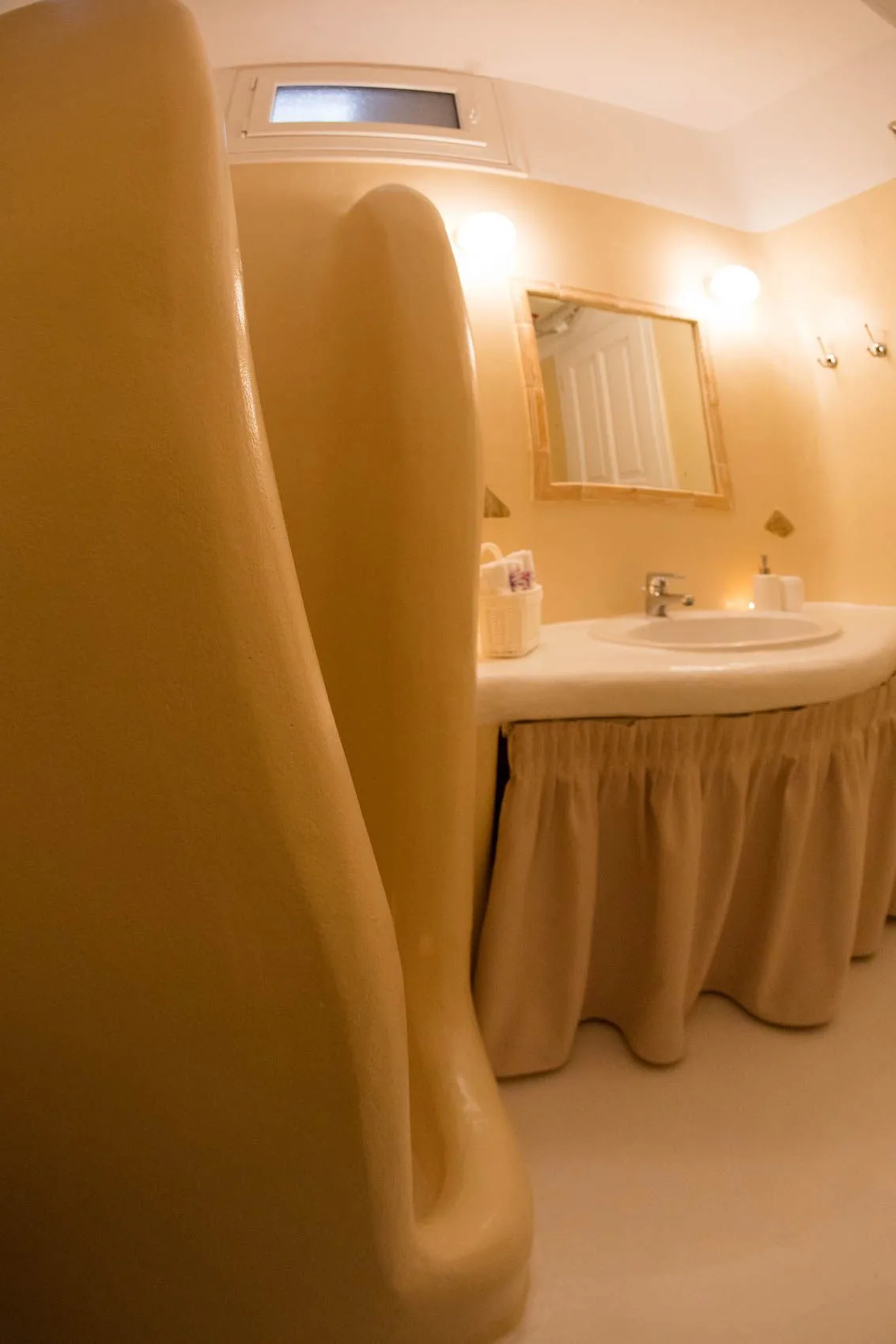 A bathroom vanity with a sink and mirror, partly obscured by a nearby fixture.