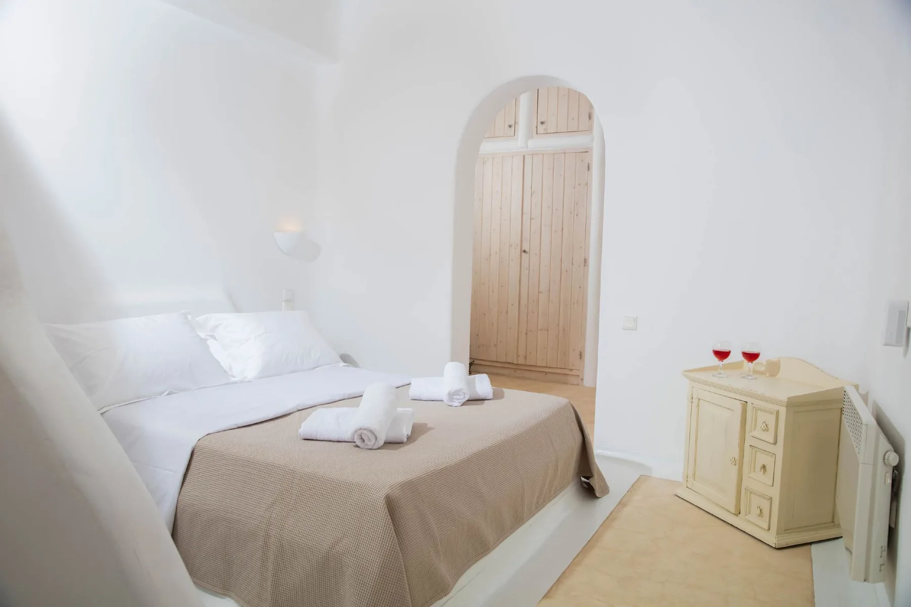 A bedroom with a bed, light bedding, and a wooden door.