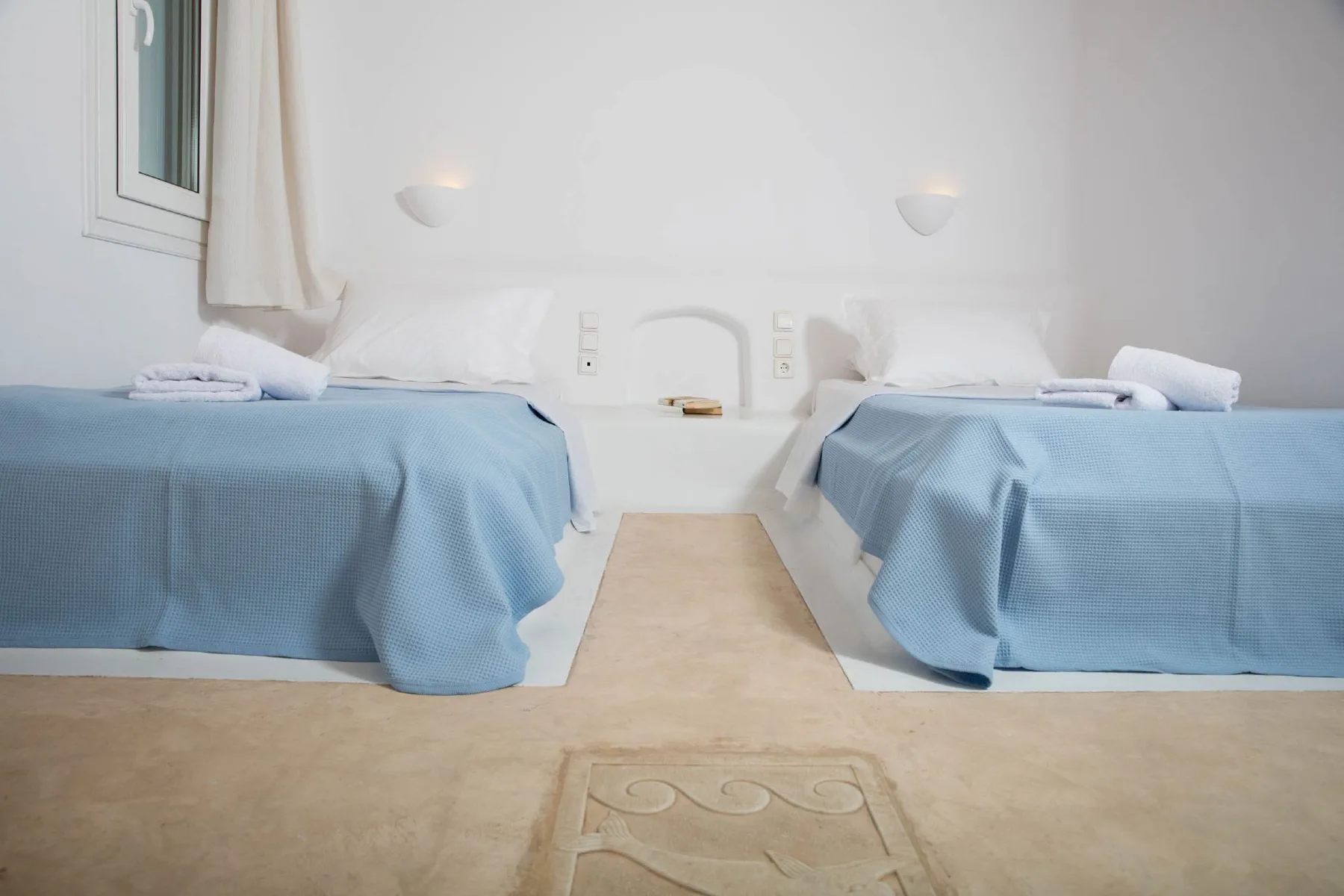 A bedroom with two beds covered in blue bedspreads.