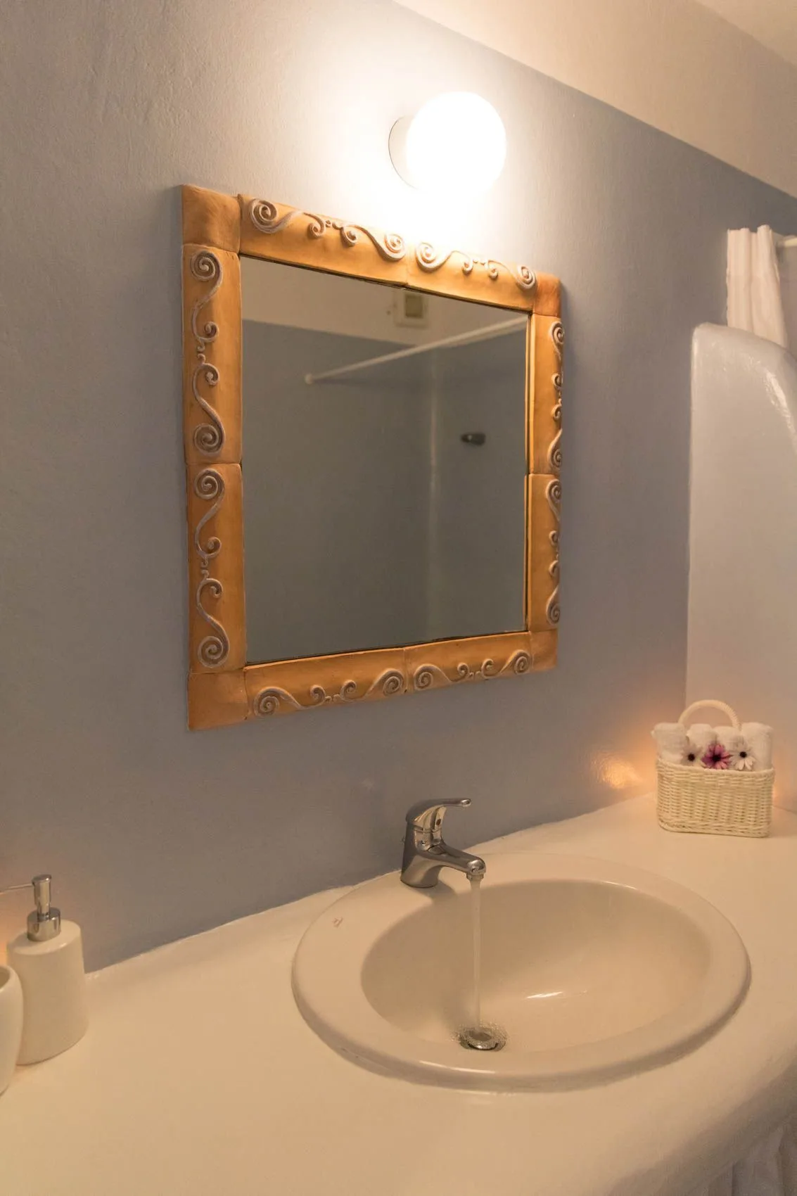 A bathroom vanity with a sink, wall mirror, and light.