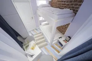 Representative hotel space: A compact bedroom with a raised bed and striped steps.