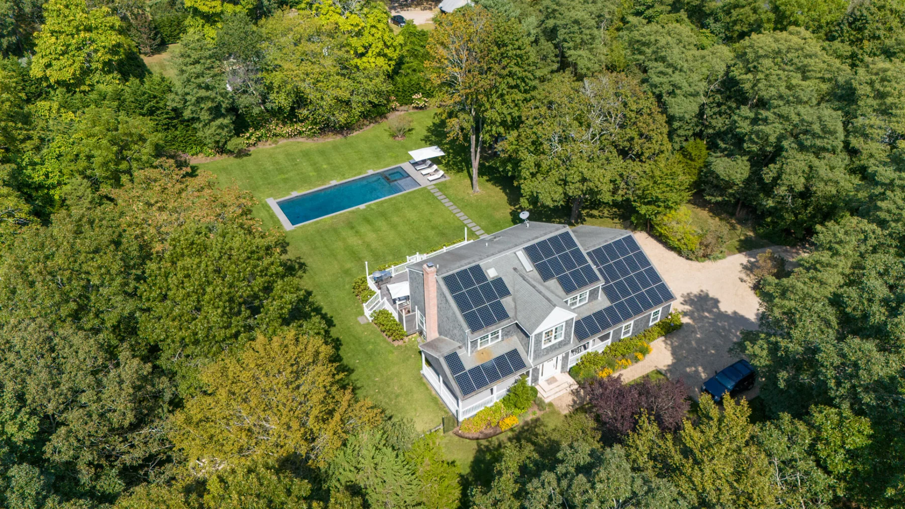 Vista aérea de una casa con paneles solares junto a una piscina.