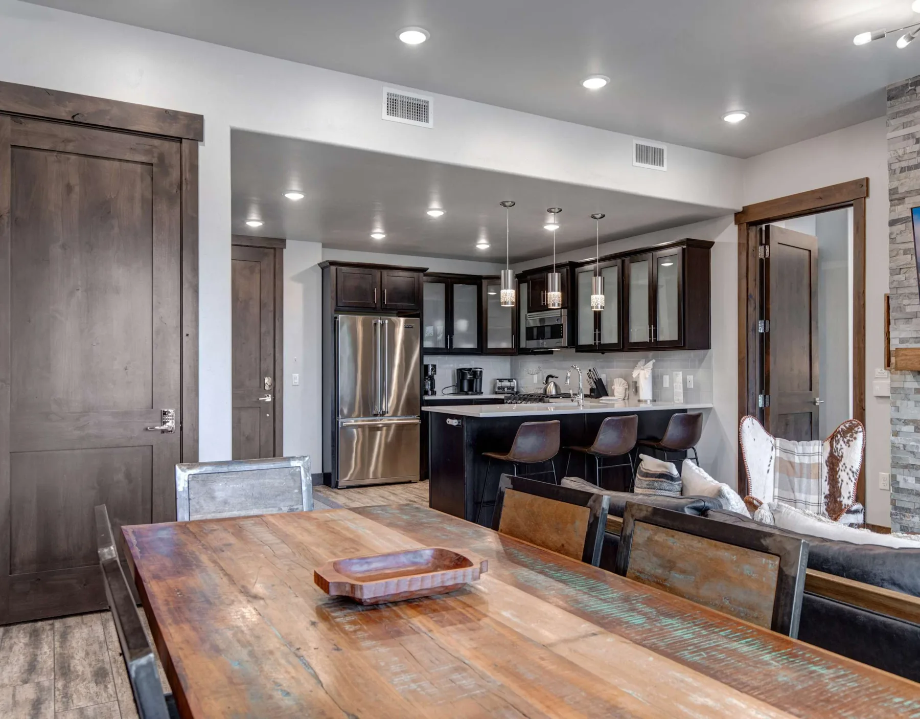 Una cocina abierta al salón con una mesa de madera en primer plano.