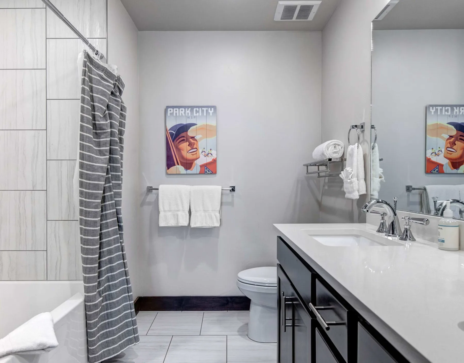 Un baño con un tocador largo, lavabo y cortina de ducha a rayas.