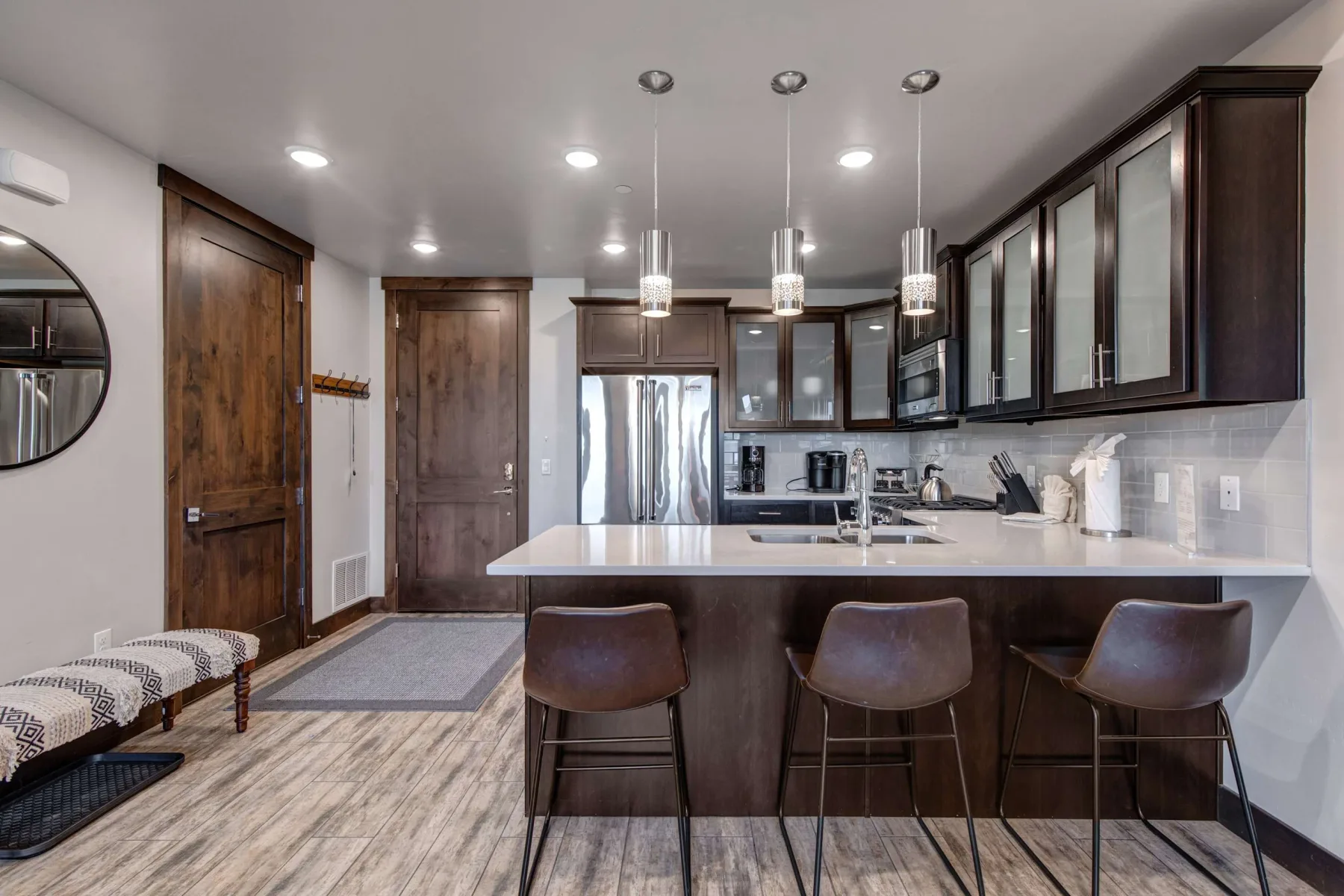Una cocina moderna con una isla central, asientos de barra y electrodomésticos de acero inoxidable.