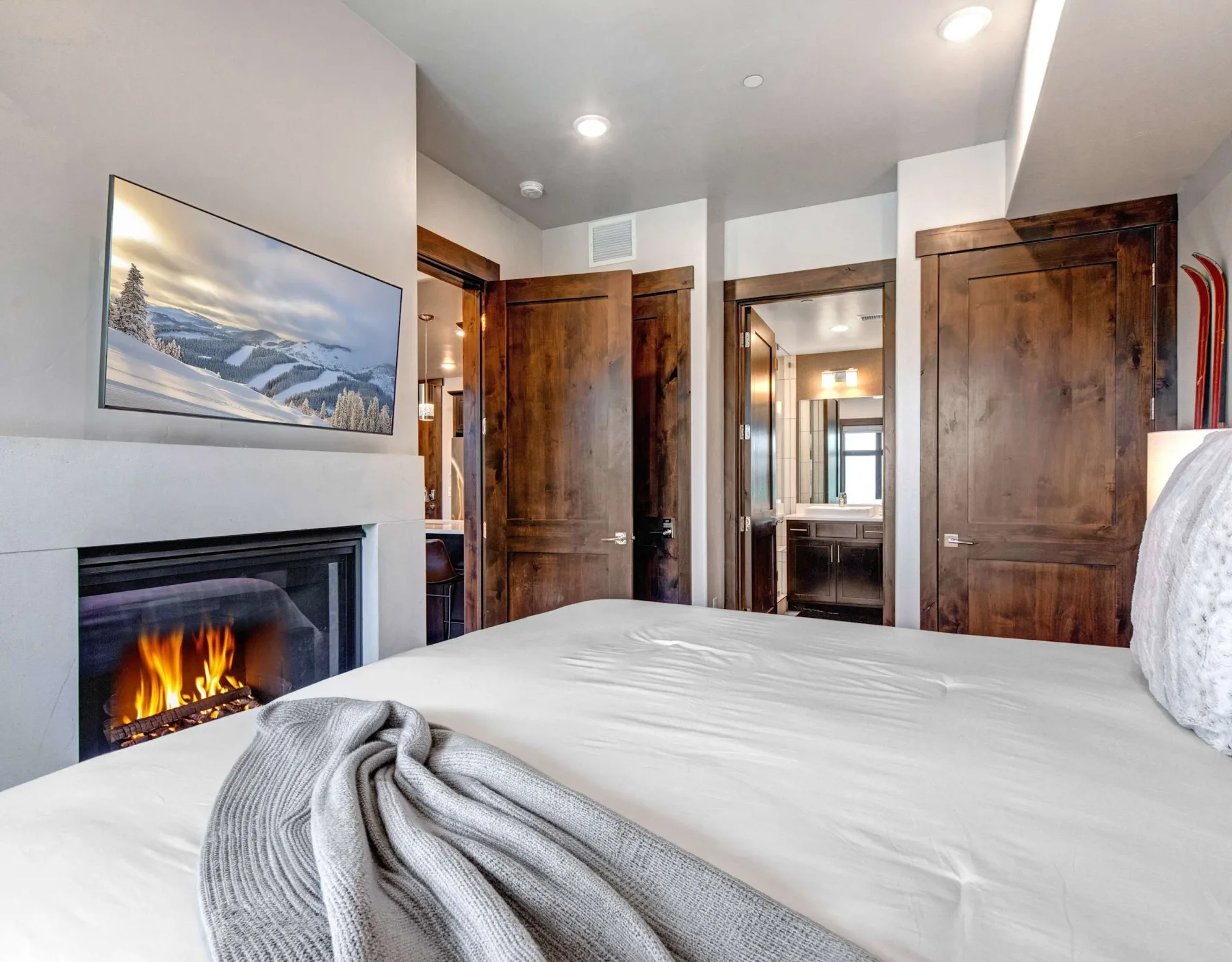 Un dormitorio con una cama tendida, una chimenea y puertas de madera.