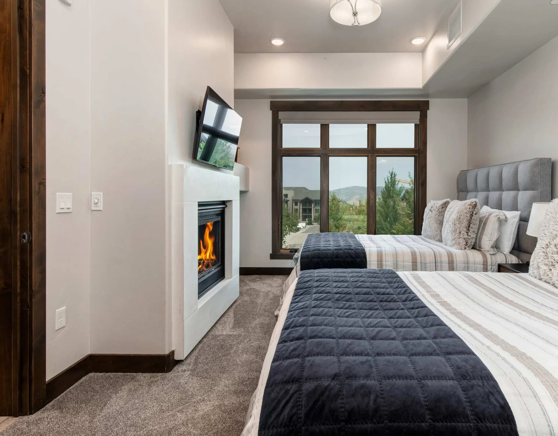 Dormitorio con dos camas, una chimenea y una ventana grande.