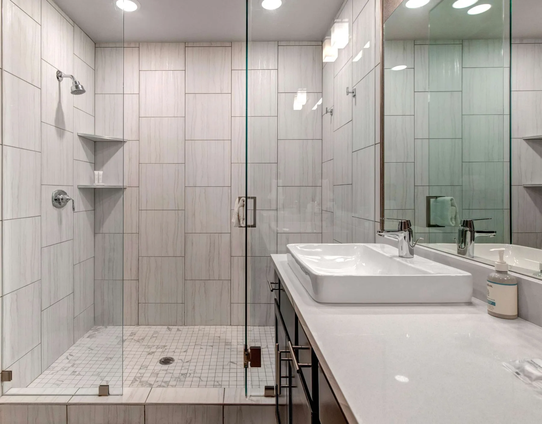 Un baño moderno con ducha de vidrio y un amplio tocador.