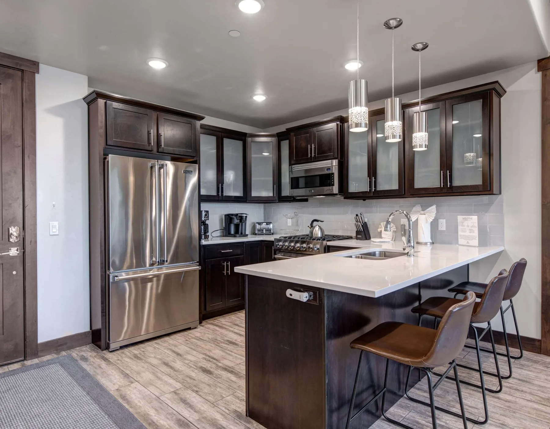 Una cocina moderna con gabinetes oscuros, electrodomésticos de acero inoxidable y una isla grande.