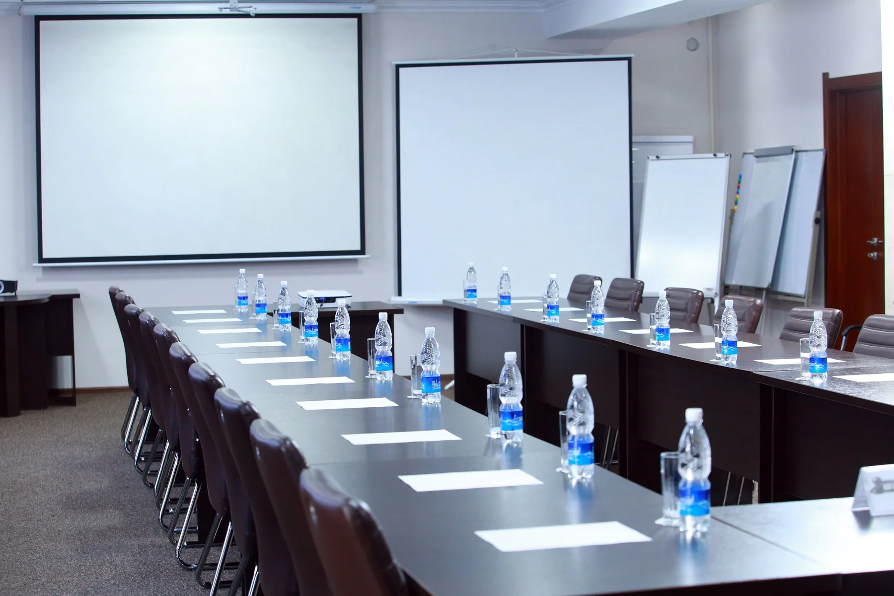 Representative hotel space: Conference room with a long table, chairs, and presentation screens.