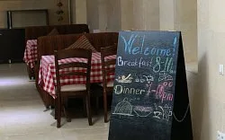 Representative hotel space: Dining area with wooden tables and a chalkboard menu beside the entrance.