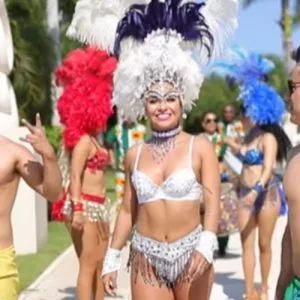 Representative hotel space: A costumed parade performer walks outdoors among other performers in colorful feathered headdresses.