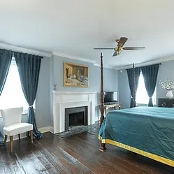 Representative hotel space: A bedroom with a fireplace, dark curtains, and a bed.
