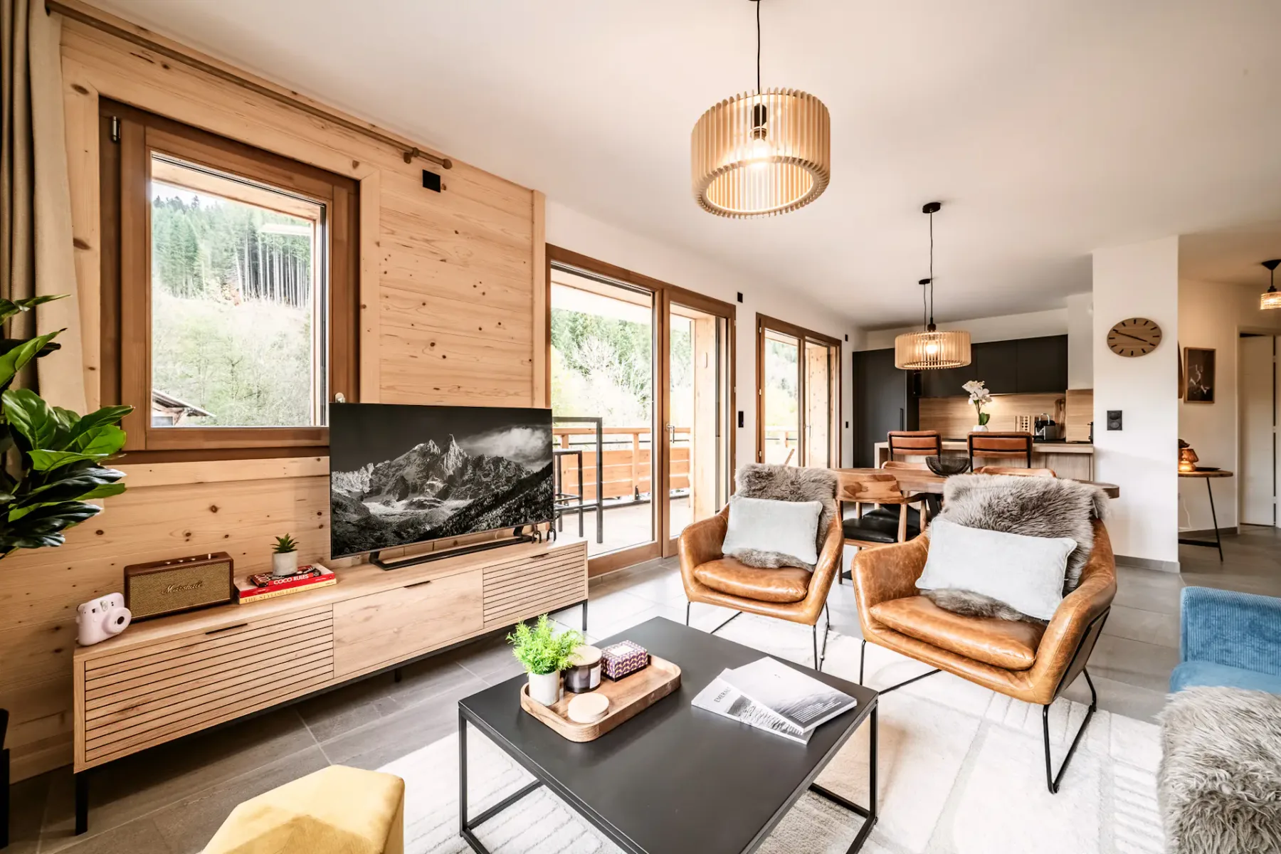 Una sala luminosa con asientos, un televisor y ventanas que dan a un balcón.