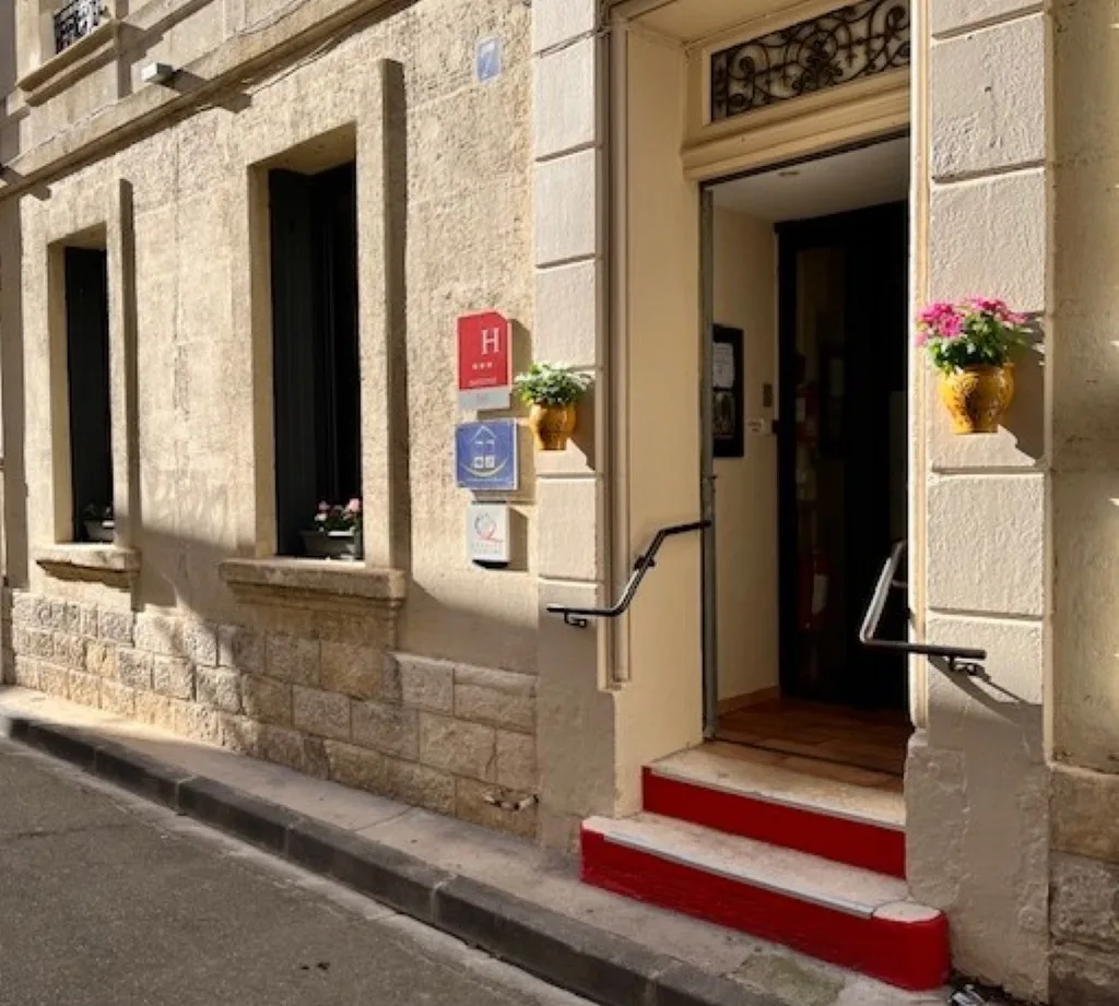 Representative hotel space: A stone building entrance opens onto the sidewalk, with flower pots beside the doorway.