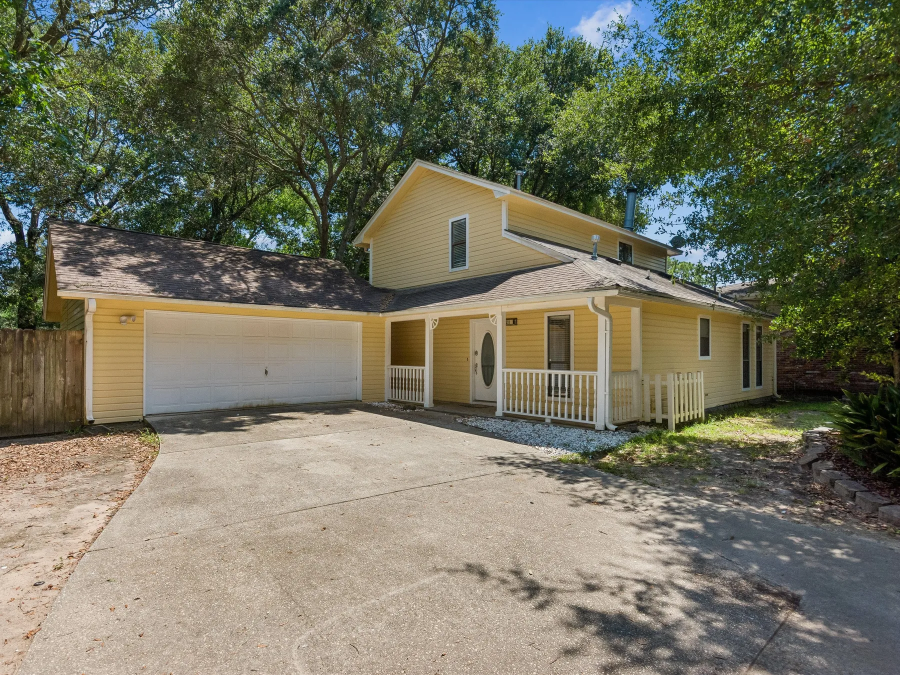 A yellow house with an attached garage and a wide paved driveway.