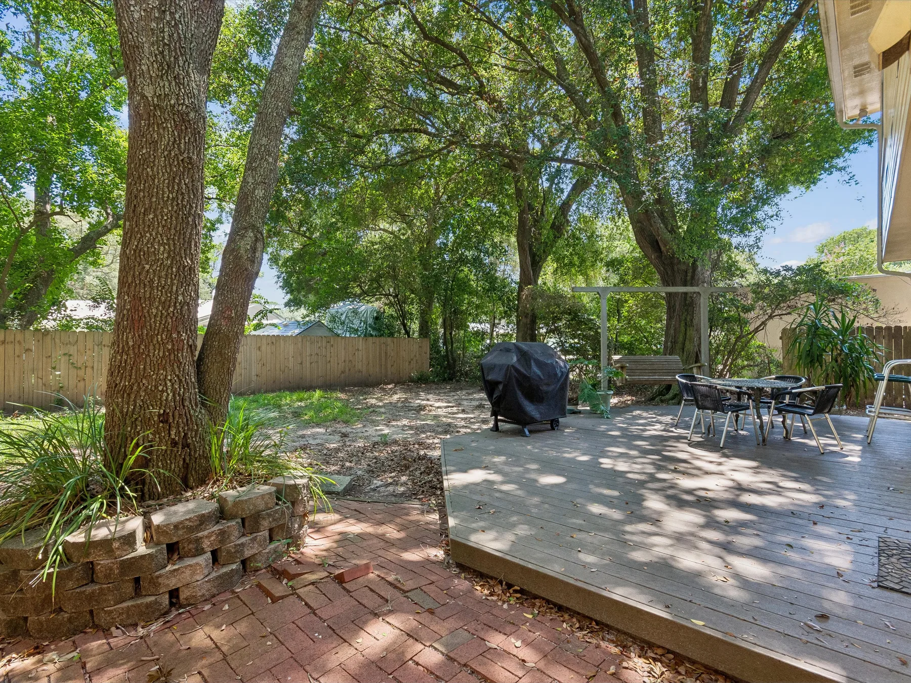 A shaded outdoor deck with seating and trees.