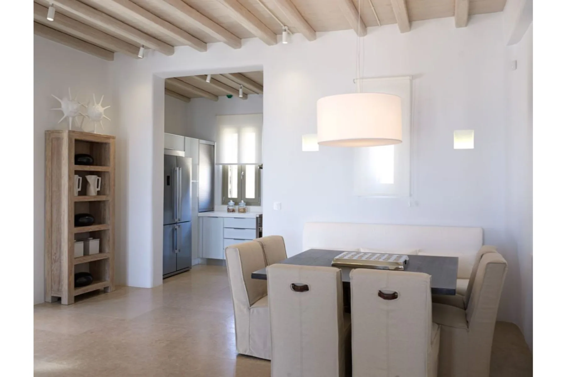 Un comedor luminoso con una mesa y asientos integrados junto a una cocina abierta.