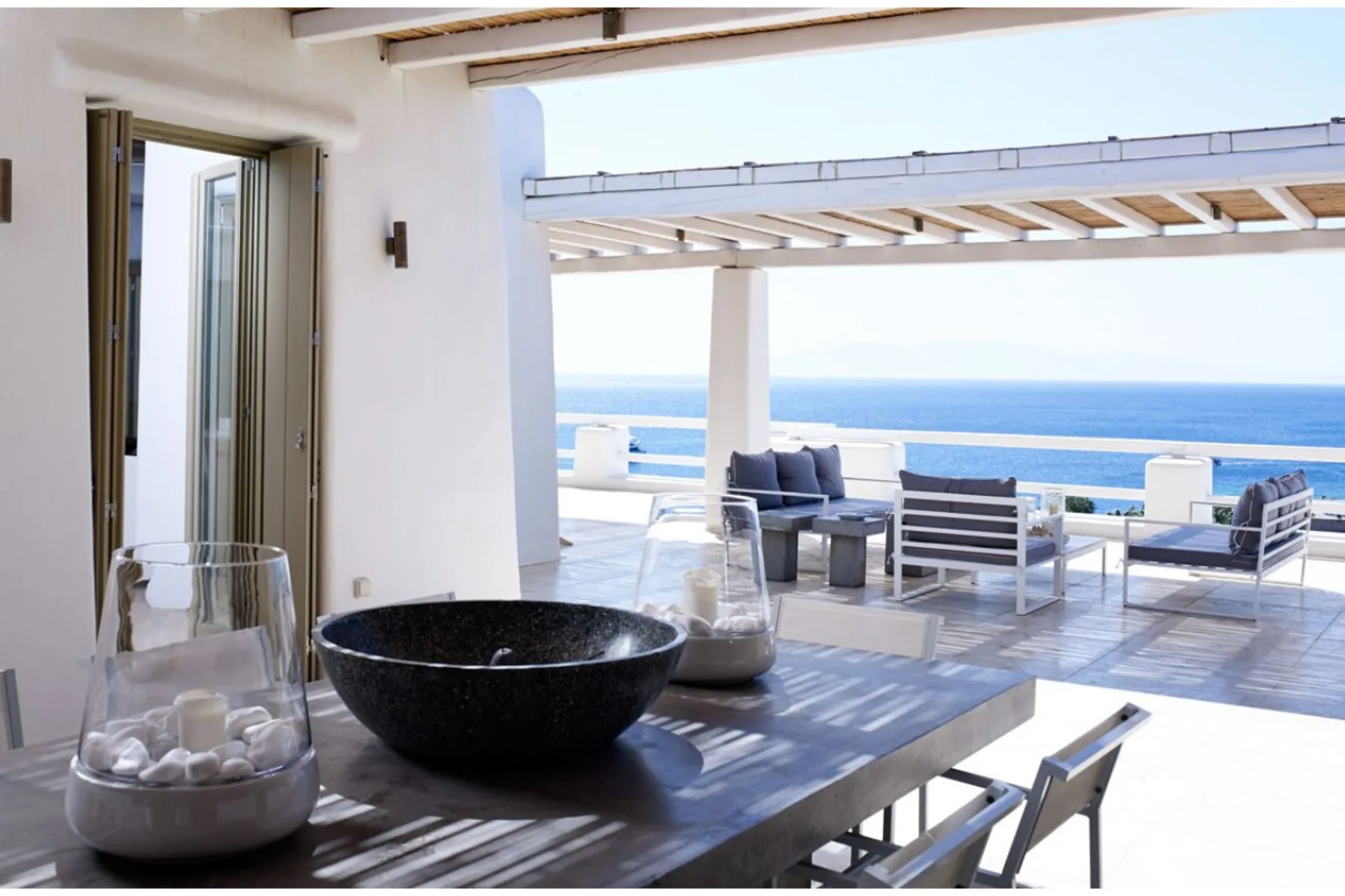 Una terraza cubierta junto al mar, con asientos al aire libre y vista al océano.