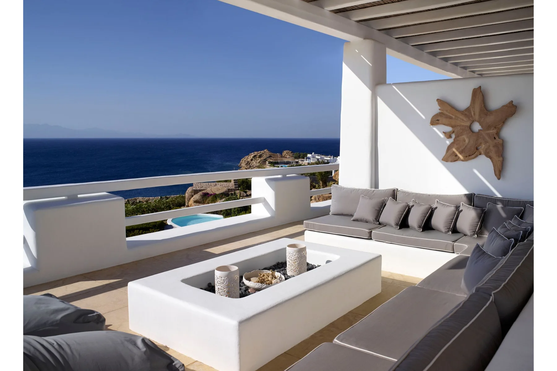 Una zona de estar exterior cubierta da al mar y tiene una mesa de centro rectangular.