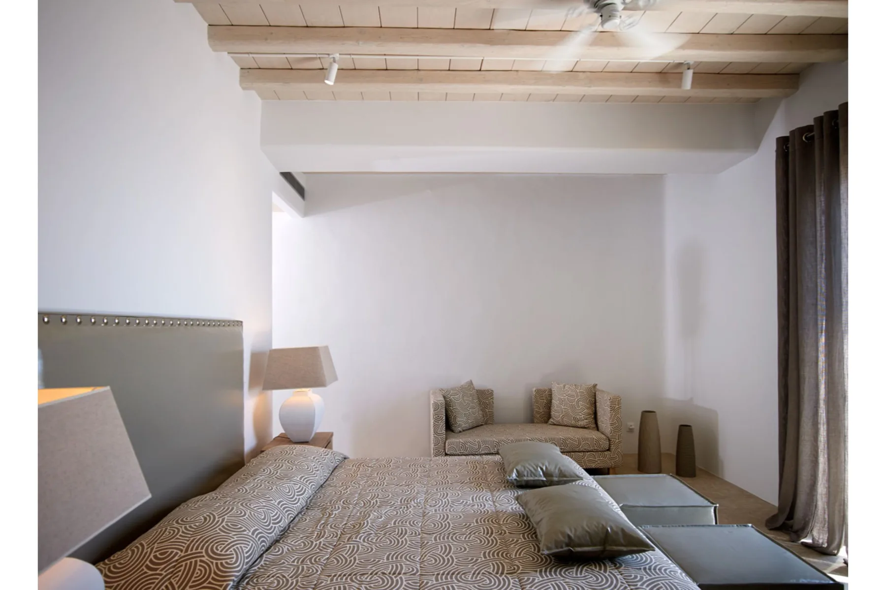 Un dormitorio con una cama, un pequeño sofá y cortinas oscuras.
