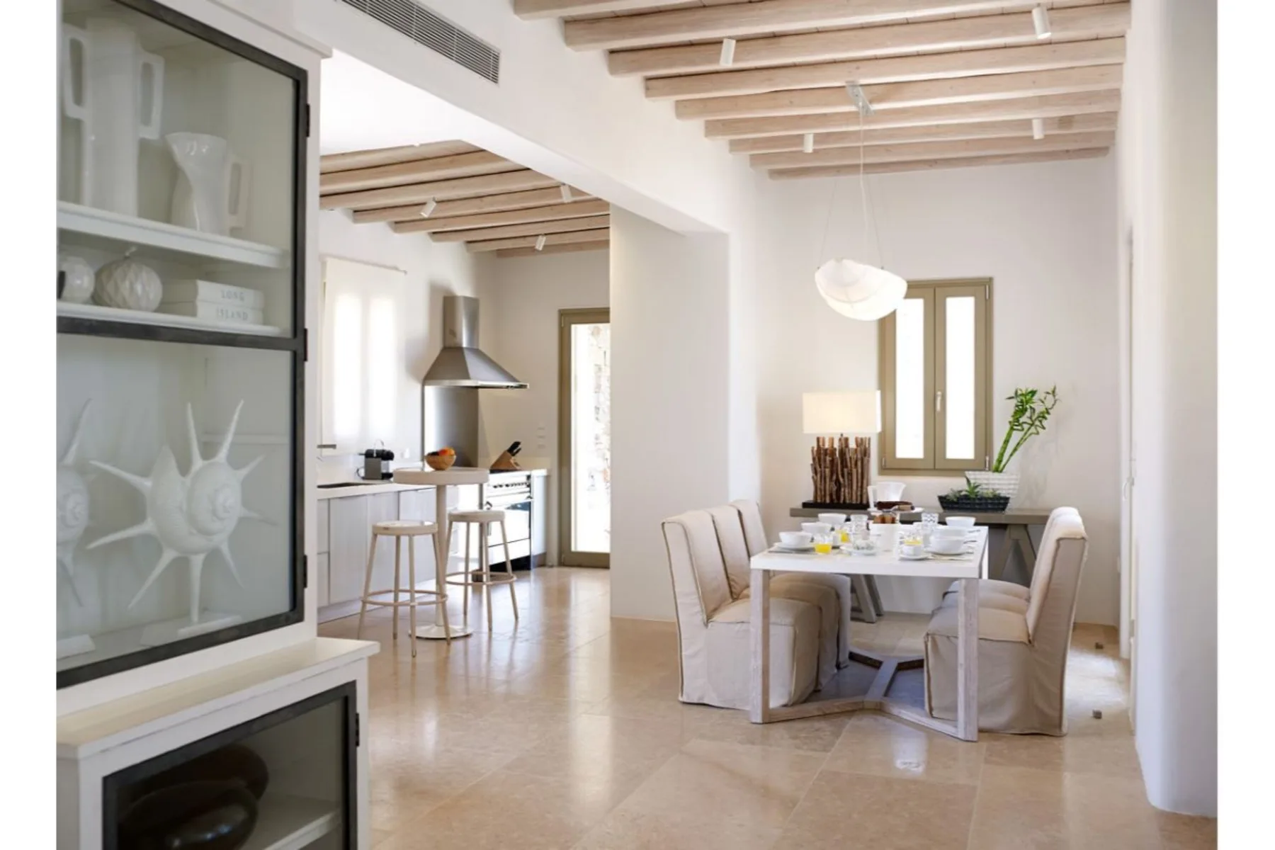 Un comedor luminoso con mesa y sillas junto a una cocina abierta.