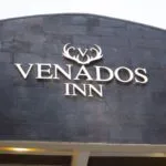 Espacio representativo del hotel: Un letrero de hotel muestra el nombre Venados Inn sobre un fondo de piedra oscura.