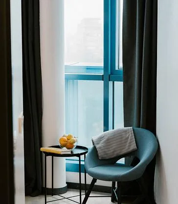 Espacio representativo del hotel: Un rincón para sentarse junto a una ventana grande con cortinas oscuras.