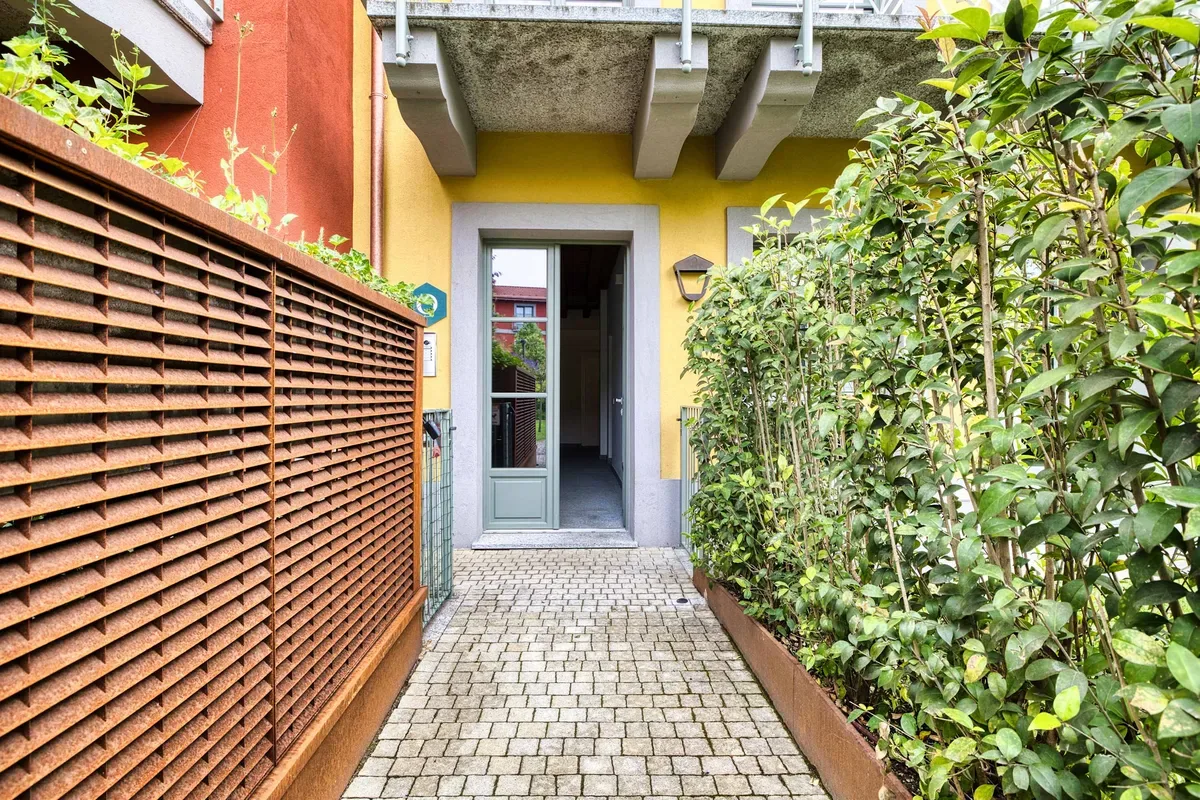 Shared amenity: A paved walkway leads to an open doorway beside a hedge.