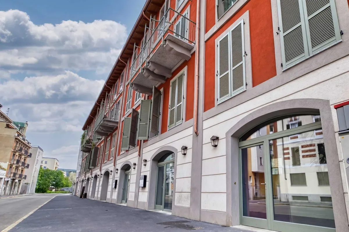 Shared amenity: A street lined with multistory buildings, with a red-orange facade and balconies.