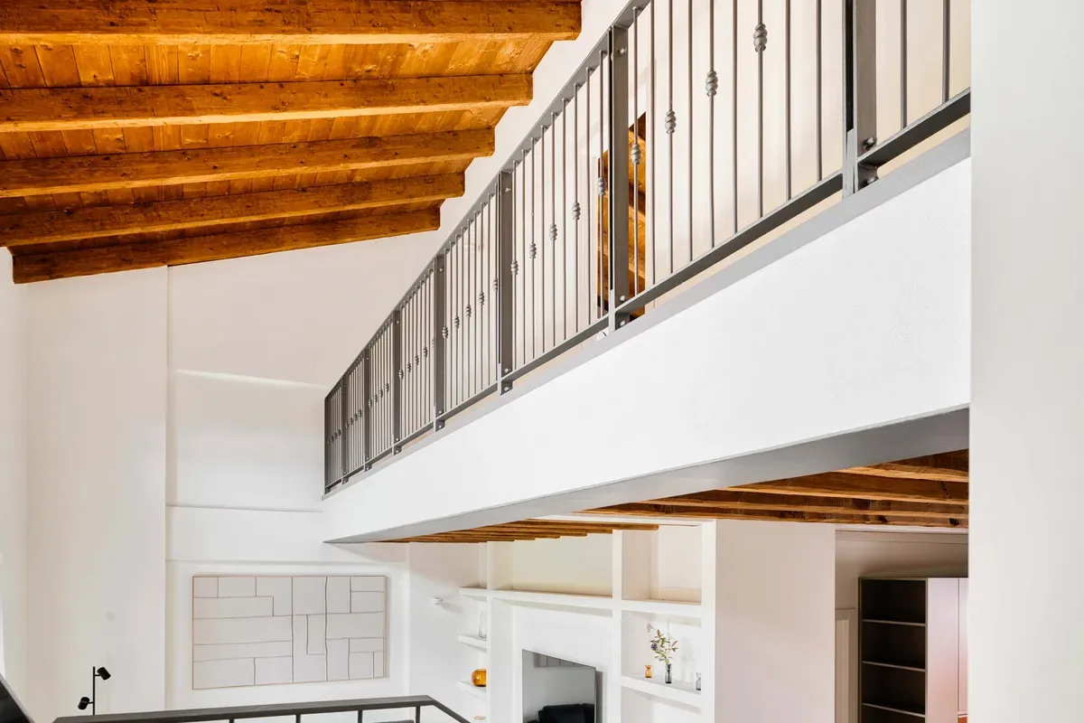 A bright interior with a wooden ceiling and an upper-level railing.