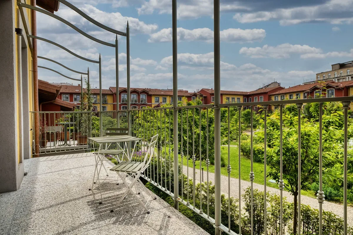 A balcony with outdoor seating overlooks a landscaped courtyard.