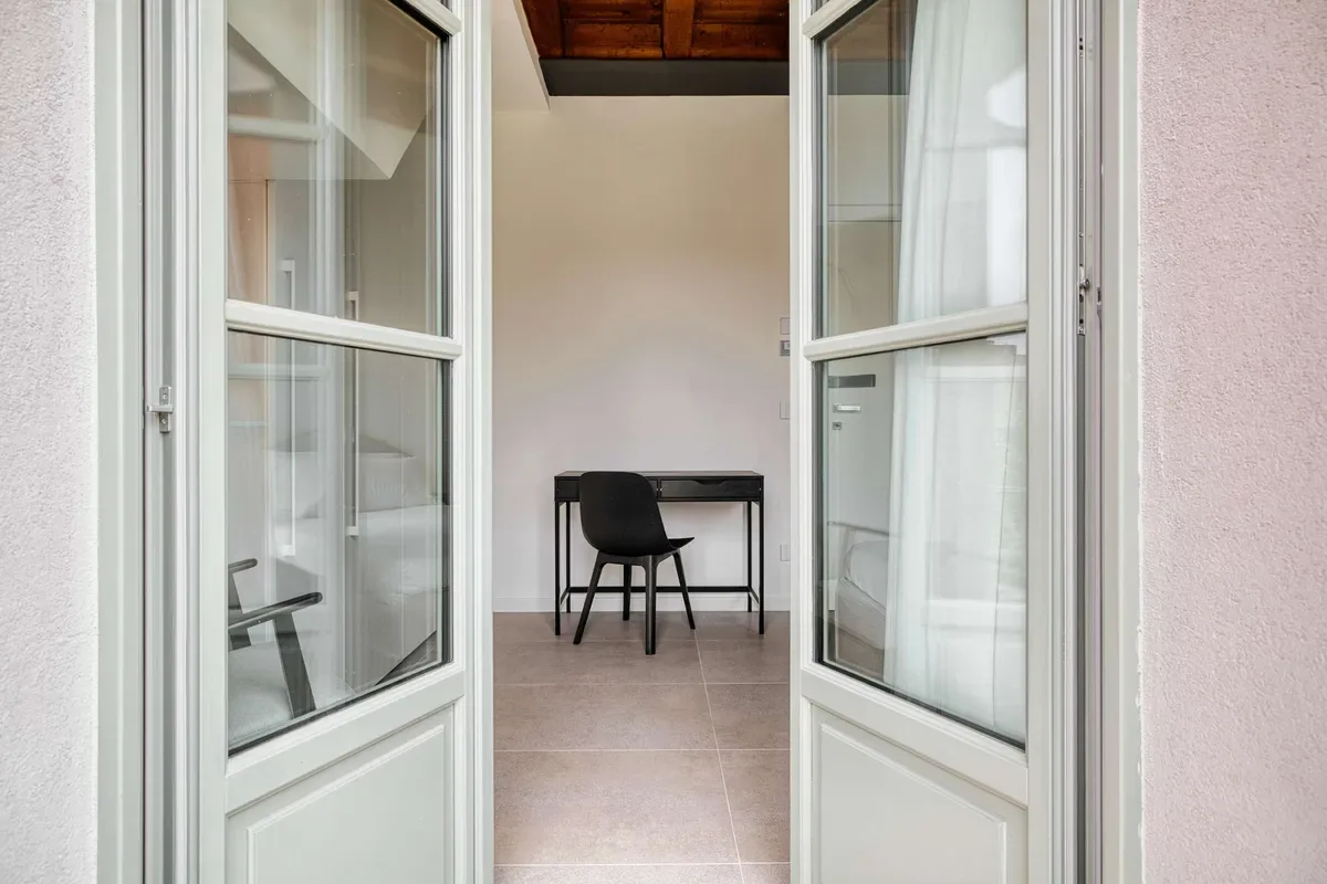 A small workspace with a desk and chair is visible beyond open glass doors.