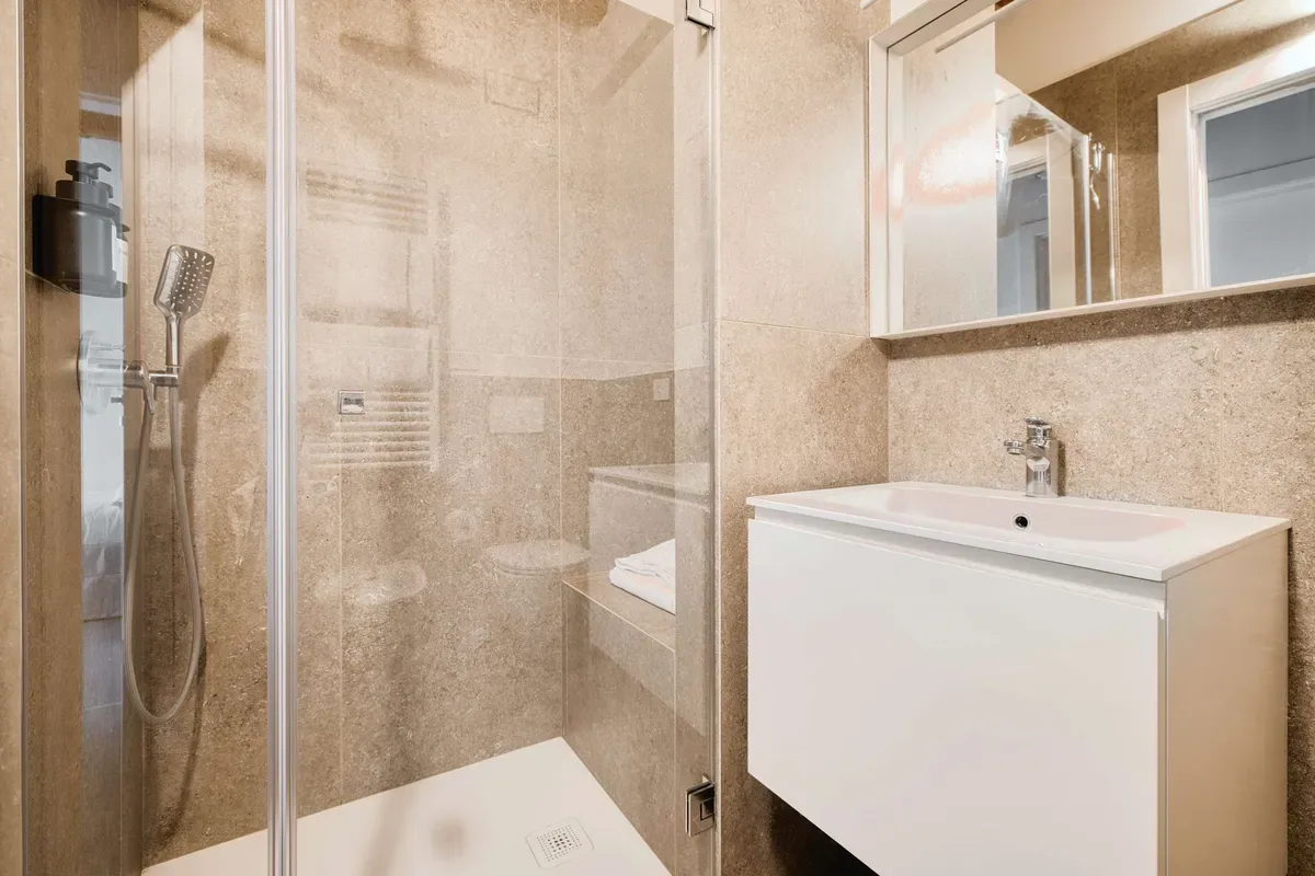 A bathroom with a glass shower and a white sink cabinet.