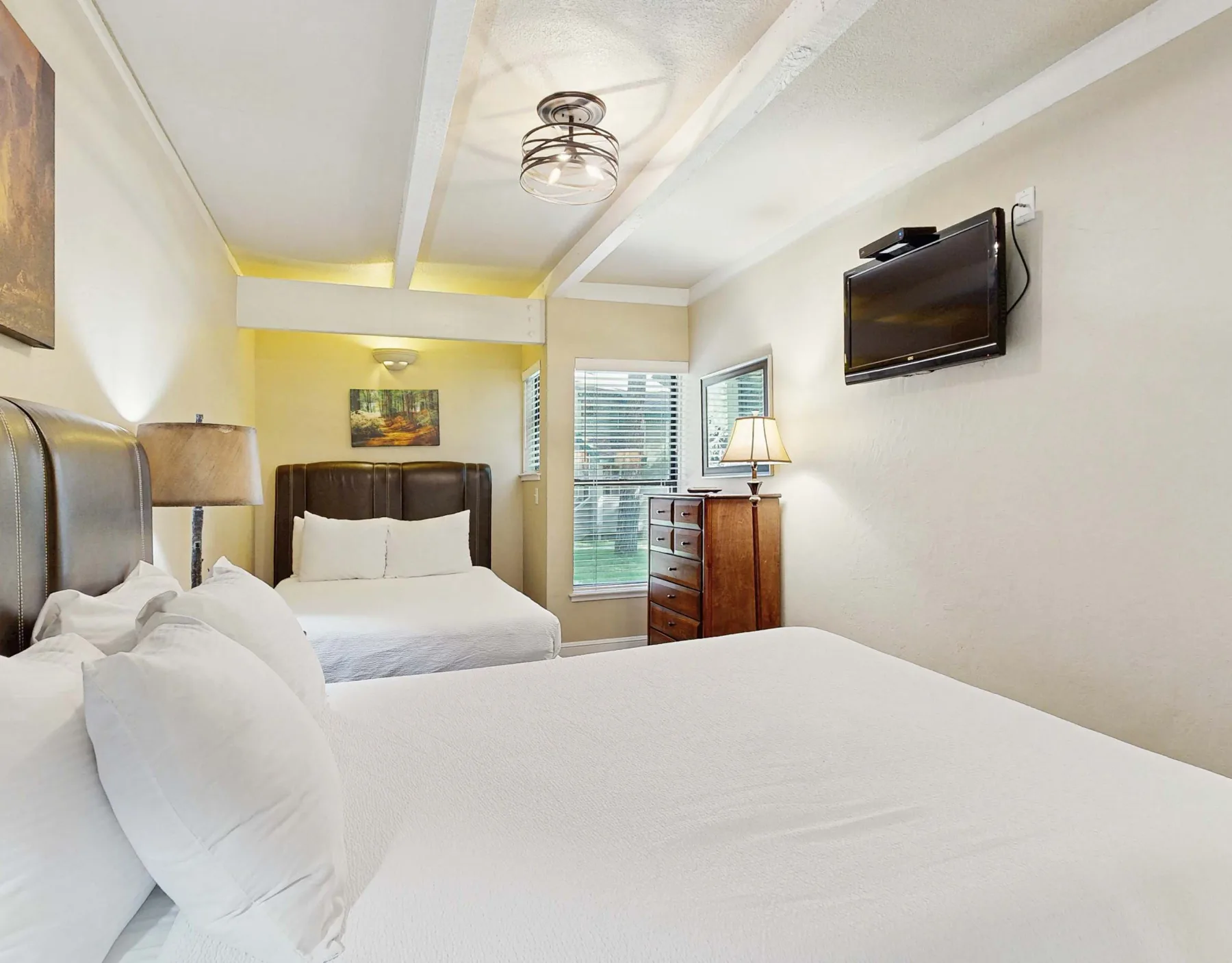 Un dormitorio con dos camas, un televisor en la pared y una cómoda.
