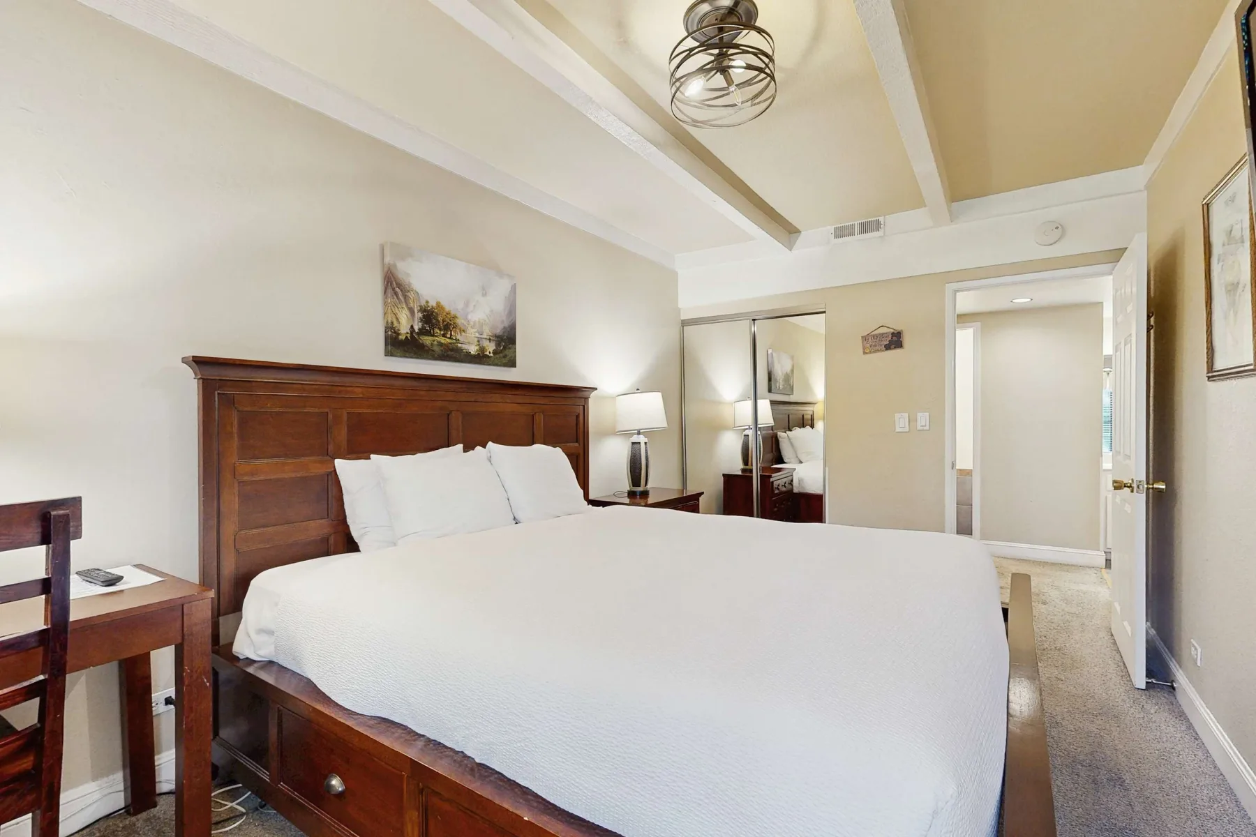 Un dormitorio con una cama grande, cabecero de madera y mesitas de noche.