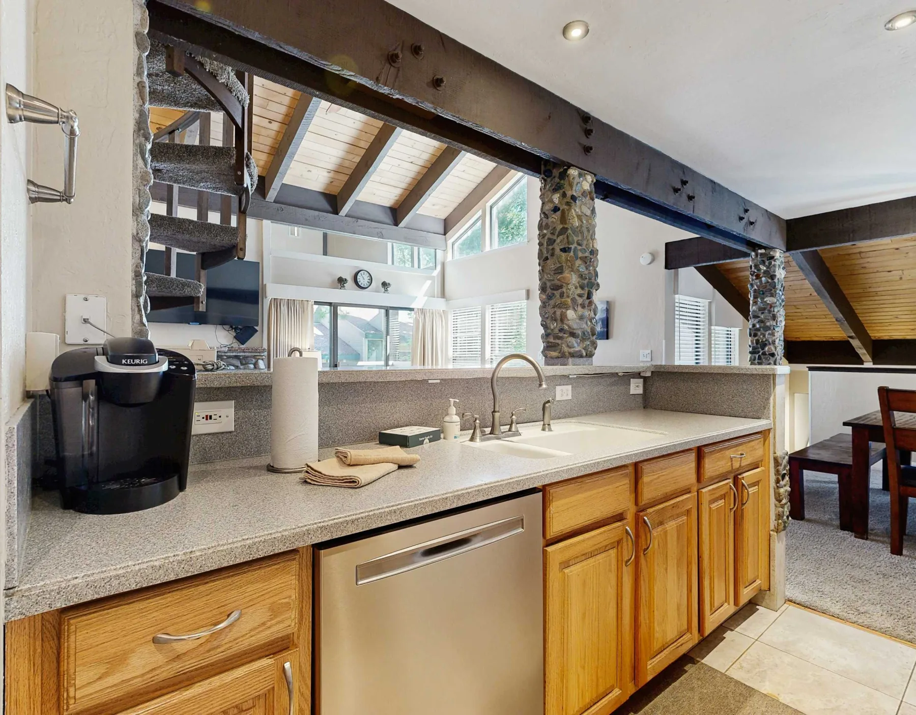 Una cocina luminosa con una encimera larga, gabinetes de madera y ventanas grandes.