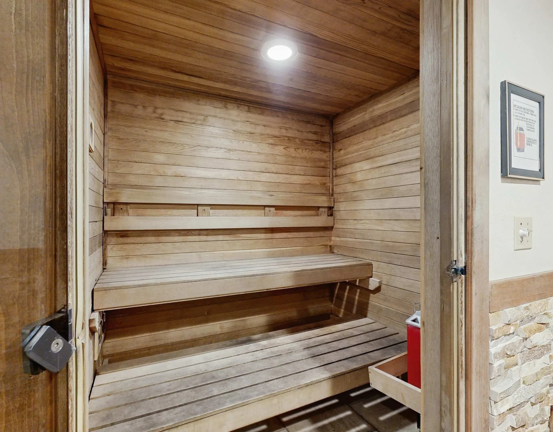 Zona común: Una sauna de madera con asientos escalonados y techo revestido de madera.