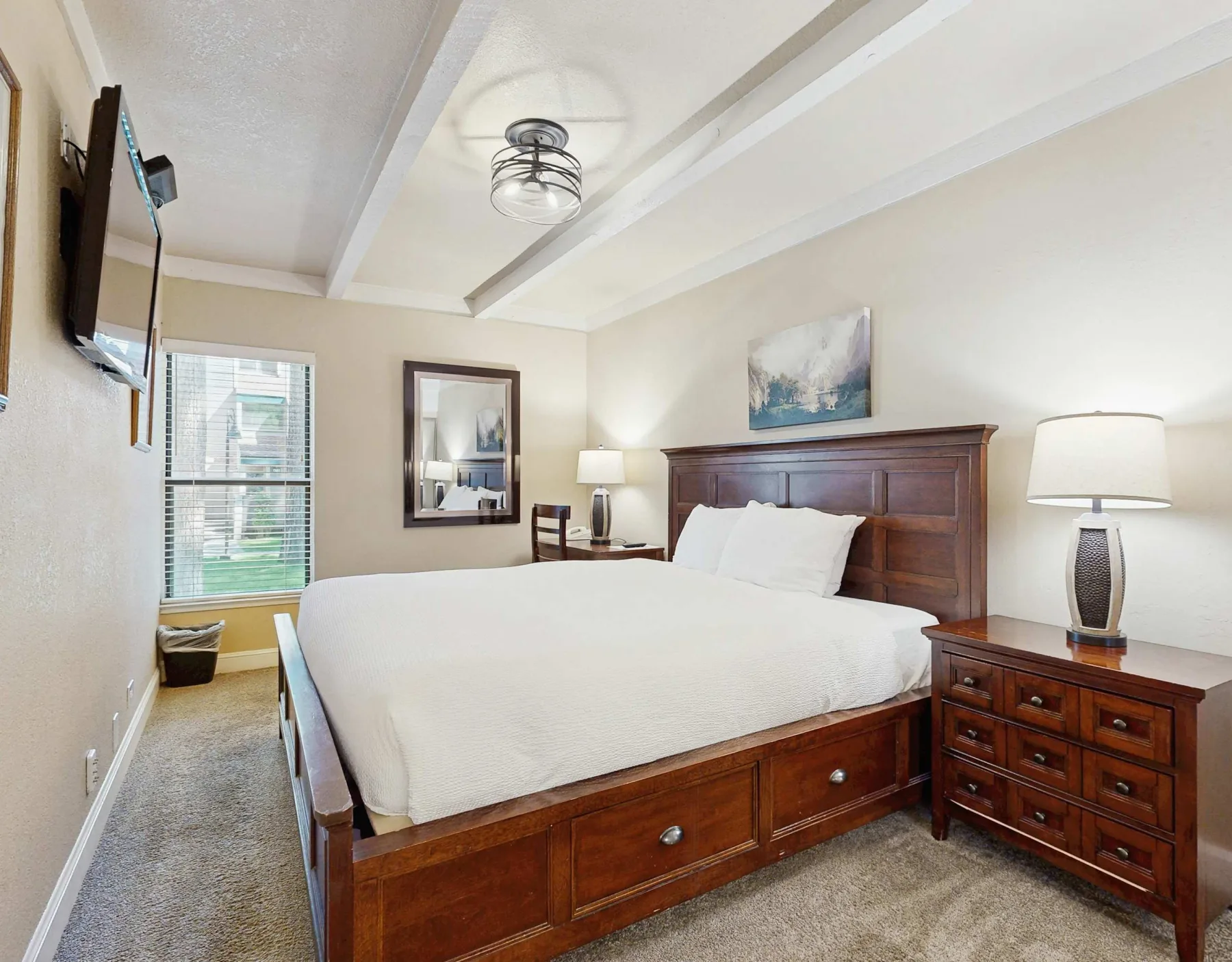Un dormitorio con una cama grande de madera, ropa de cama blanca y lámparas de noche.