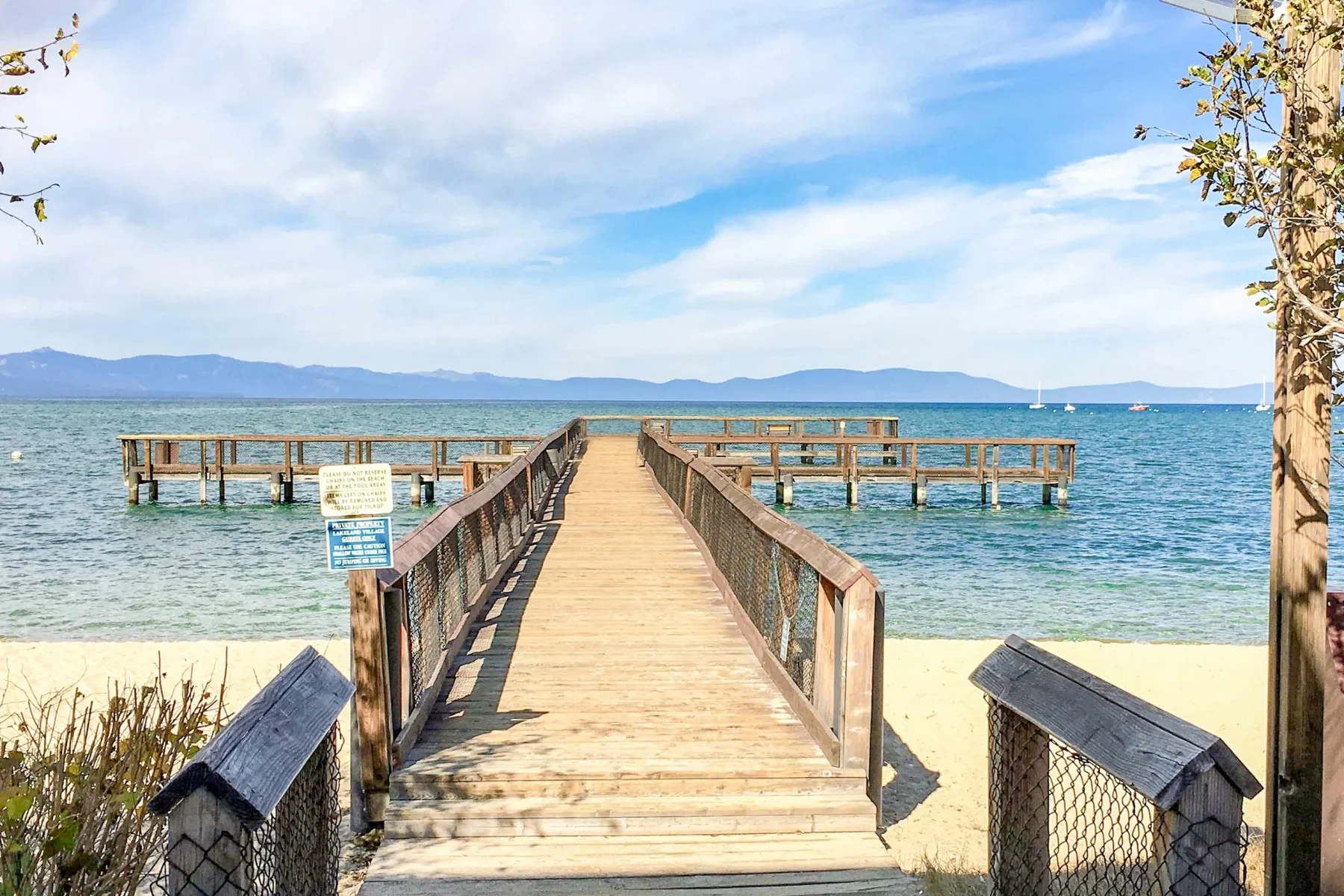 Zona común: Un muelle de madera se extiende desde una playa arenosa hacia el lago.