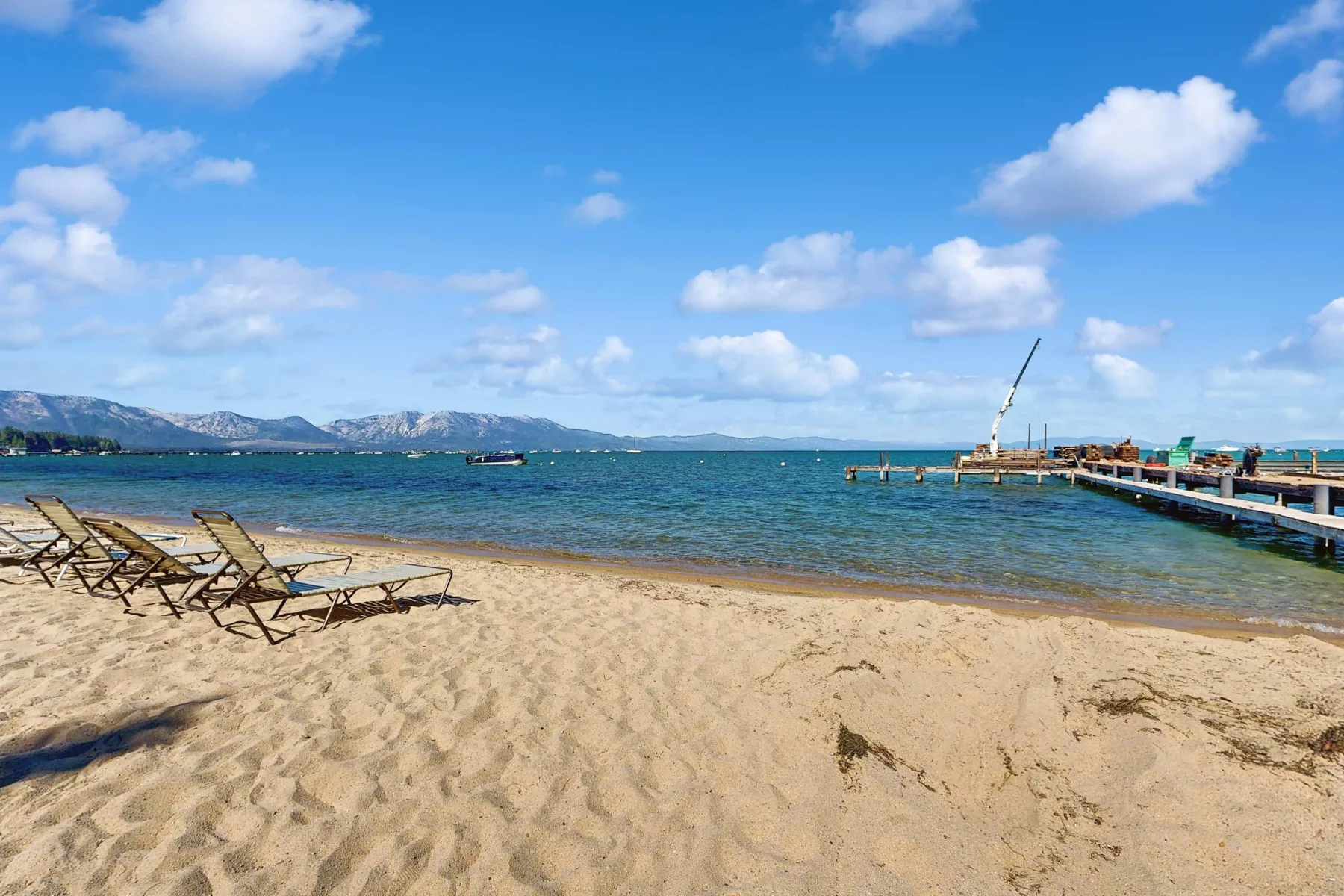 Zona común: Una playa de arena con tumbonas junto al agua y un muelle.