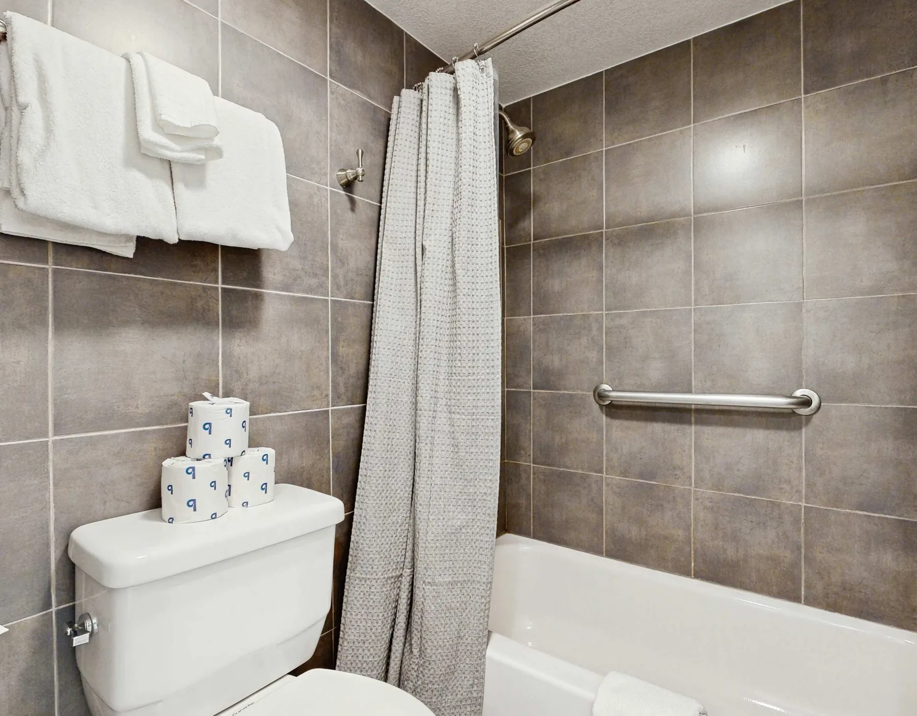 Un baño alicatado con bañera, cortina de ducha y barra para toallas.