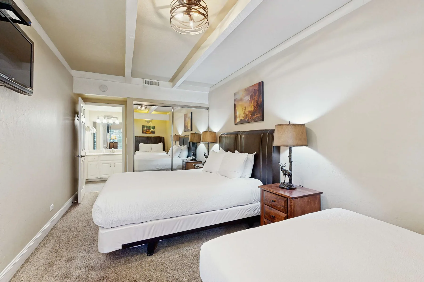 Un dormitorio luminoso con ropa de cama blanca, cabeceros oscuros y mesillas.