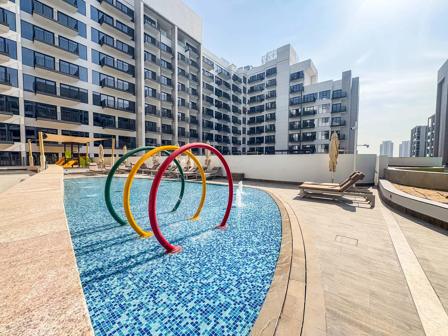 Zona común: Una piscina al aire libre con arcos de colores y asientos de descanso.