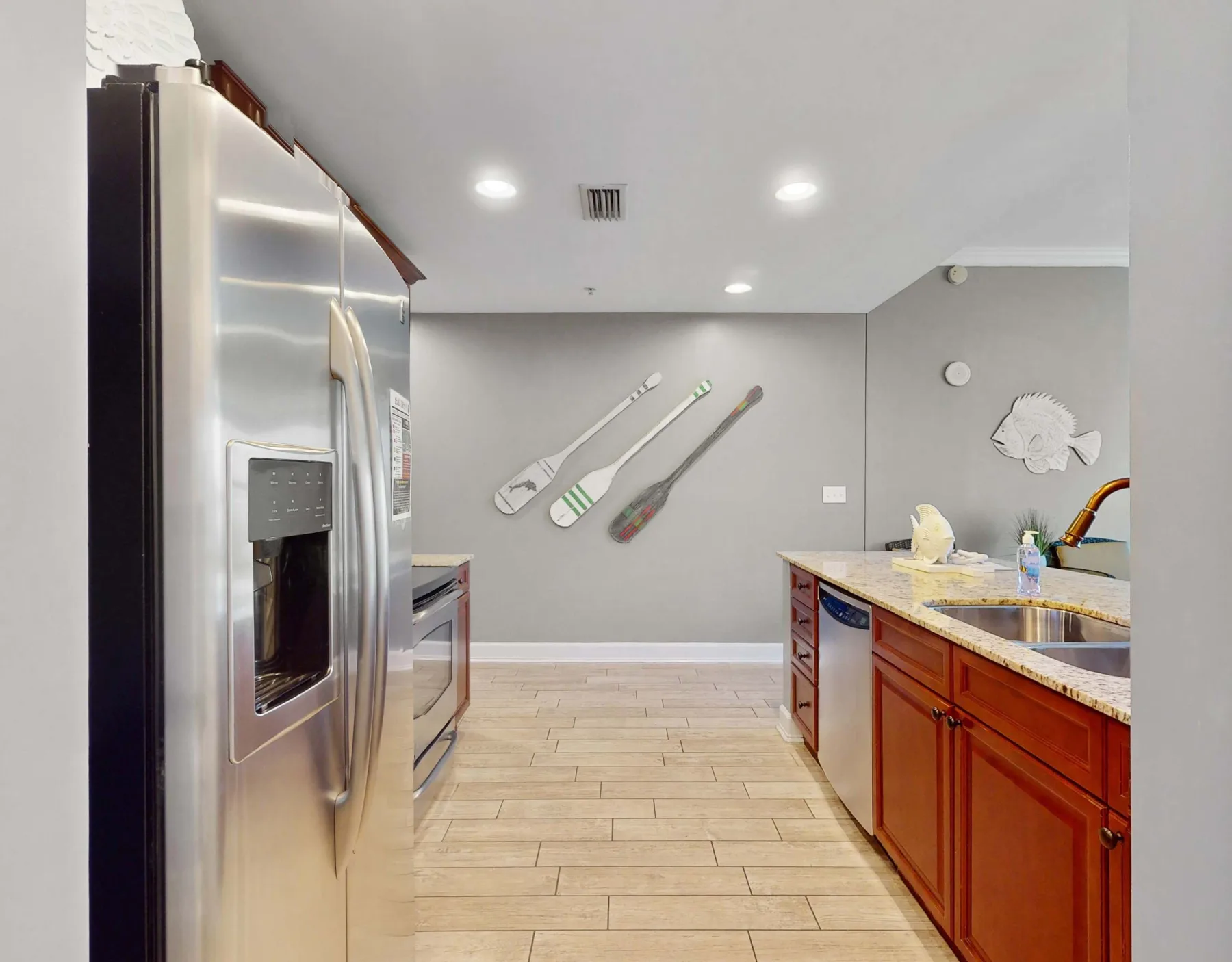 A kitchen with wooden cabinetry, a refrigerator, and decorative paddles on the wall.