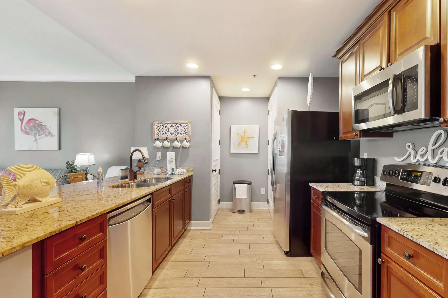 A kitchen with a long counter, wooden cabinets, and stainless steel appliances.