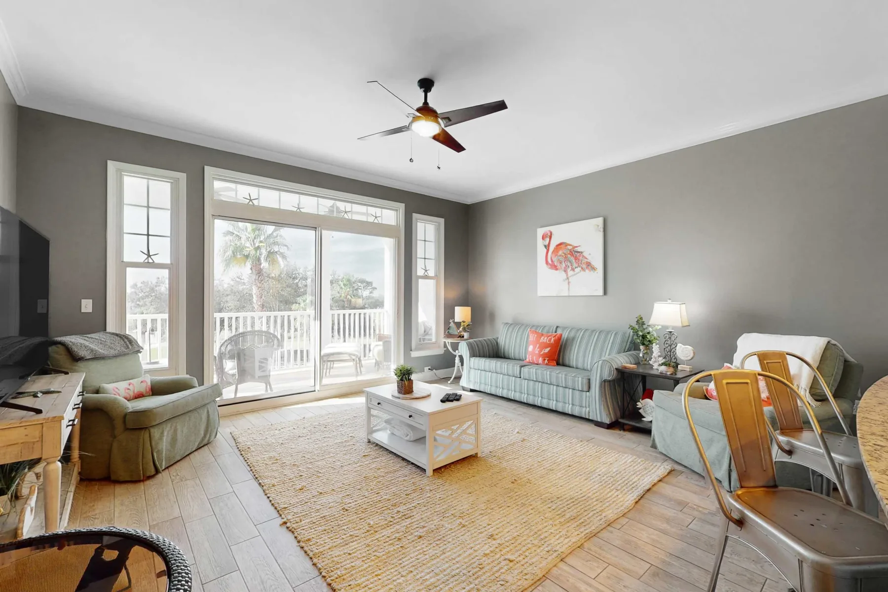 A bright living room with seating, a coffee table, and glass doors opening to a balcony.