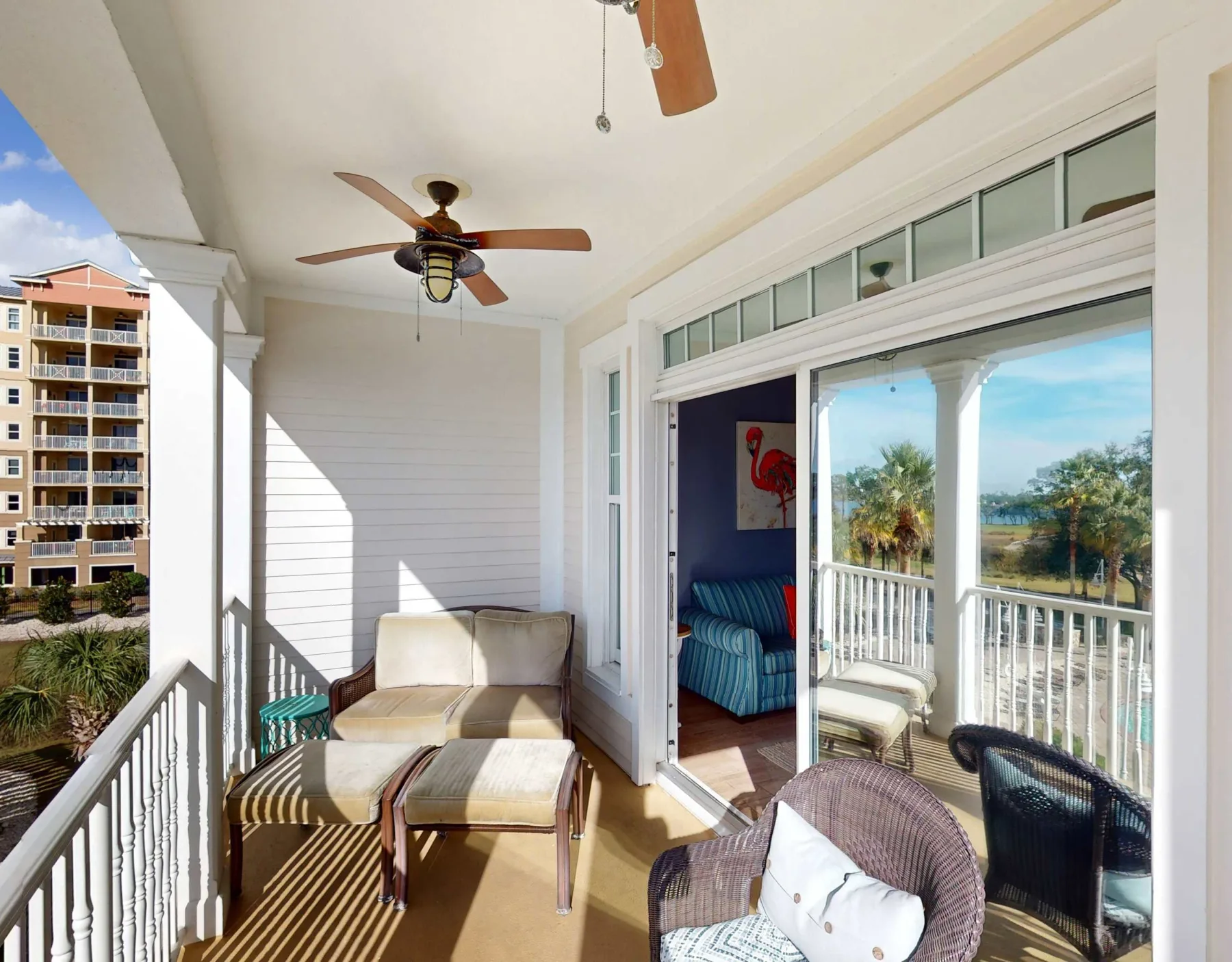 A bright covered balcony with seating and sliding glass doors.