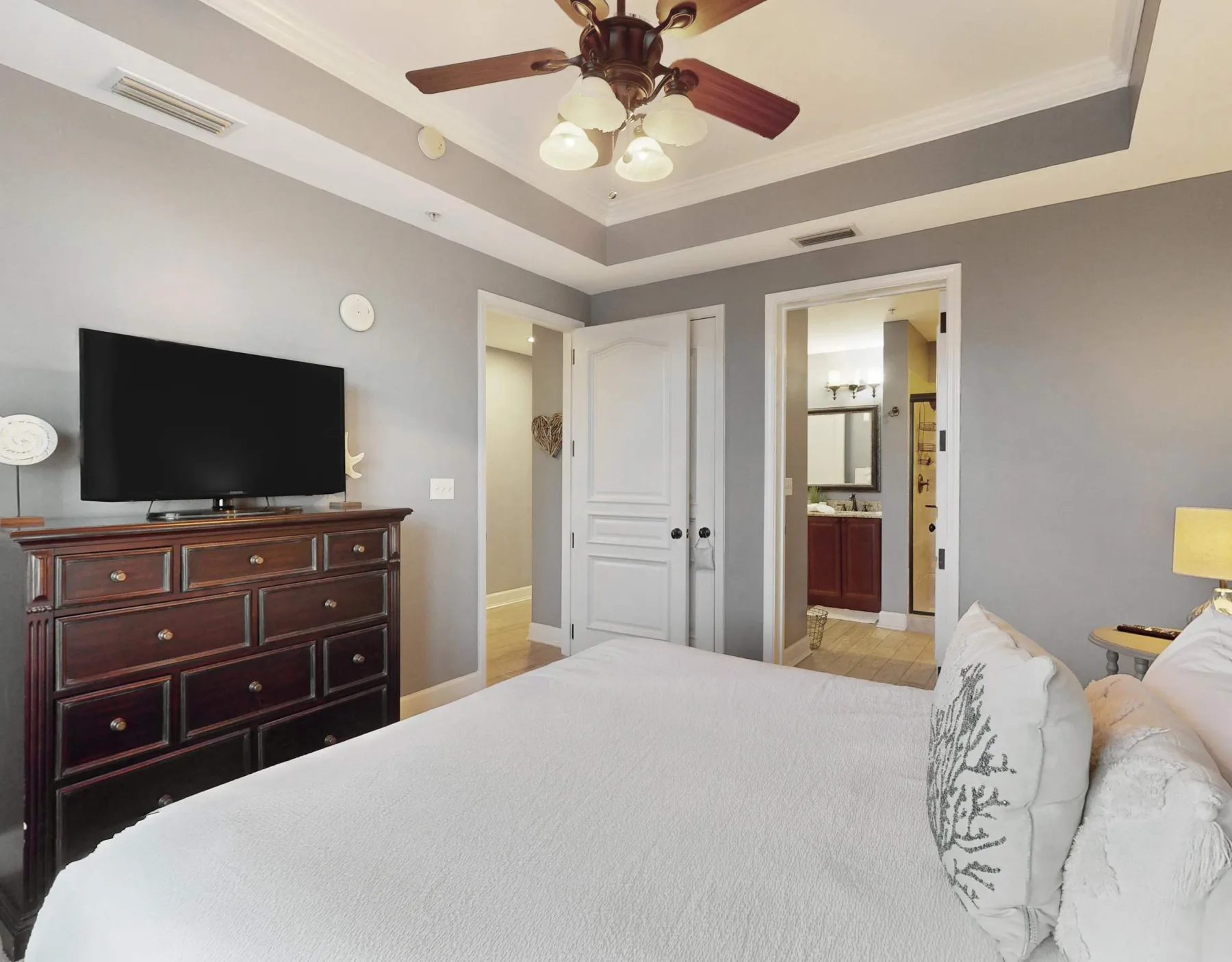 A bedroom with a bed, television, and ceiling fan.