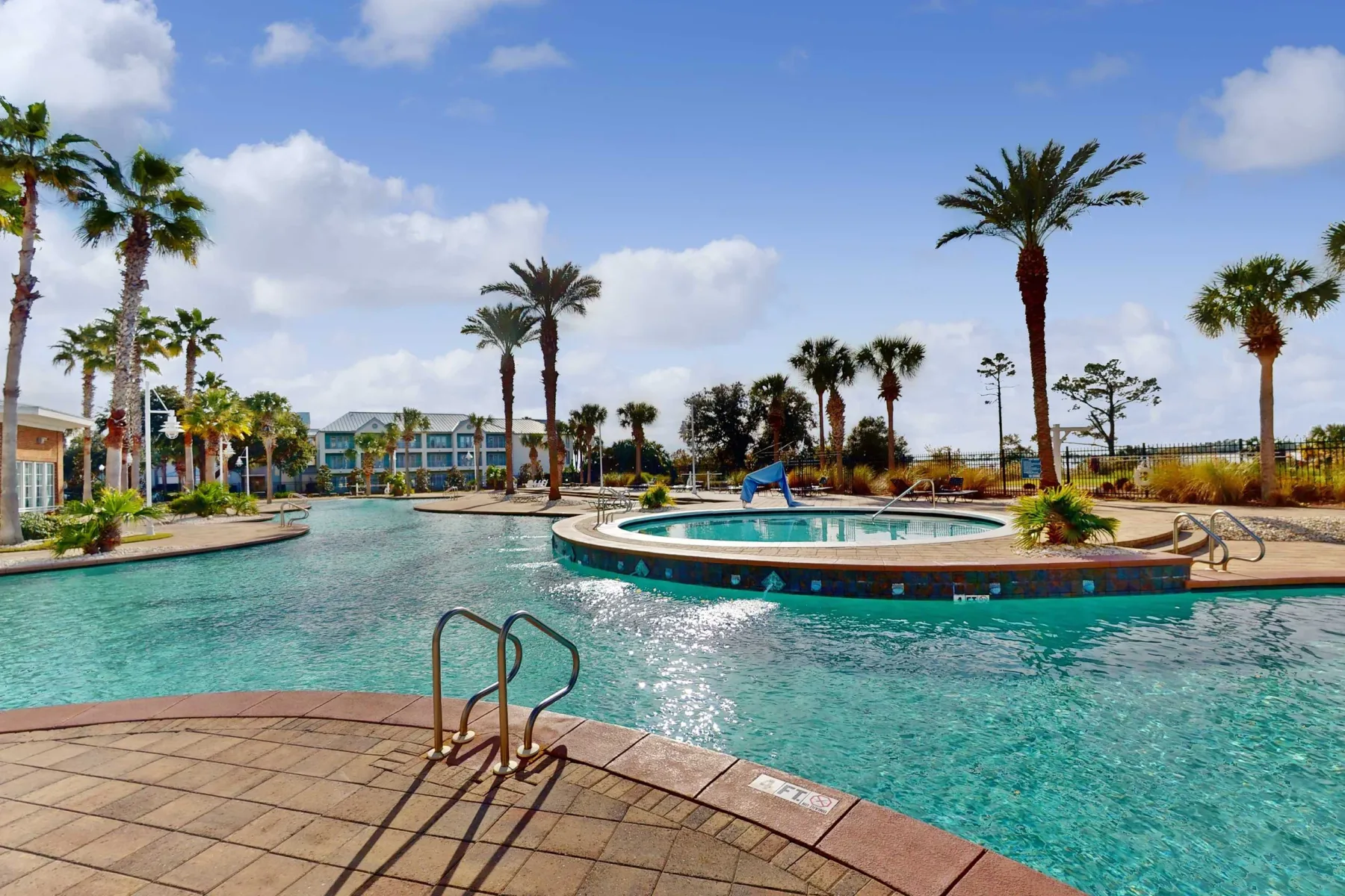 Shared amenity: An outdoor swimming pool surrounds a raised circular pool beneath palm trees.